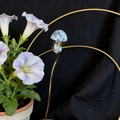 Detail of blue spotted crystal mushroom on golden wire stand with purple flowers - Granite
