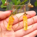 Close-up of bohemian gold hoop earrings with natural yellow crystal pillars on ear hooks - Citrine Gold Hoop