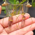 Detailed shot of large golden hoop earrings with natural brown crystal stone pendants - Brown & Gold Hoop