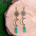 Détail de boucles d'oreilles lune et soleil avec cristal vert sur fond de mousse naturelle - Cristal Vert