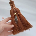 Close-up of a mini witch broom car pendant with skull hand and gold bead detail - Skeleton Hand Style (03)