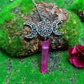 Macro shot of silver Triple Moon pendant with wrapped pink crystal on mossy stone - Natural / Triple Moon Purplish Red Crystal Necklace
