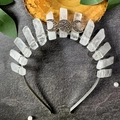 Detailed top view of a white crystal moon crown on a dark stone surface with green leaves - Clear Quartz Silver Wire Silver Headband + Triple Moon