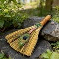 Macro detail of ritual altar broom with peacock feather, pink crystal, and dragon charm - Strawberry Quartz Viking Dragon Broom