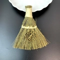 Detail of a mini straw broom with a bronze three-headed dragon charm on black background - Three-headed Dragon Style (06)