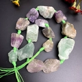 Macro detail of raw purple and green fluorite crystal strand with handmade knots - Fluorite