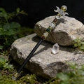 Macro view of crystal magic wand with celtic symbols and moon decor on mossy stone - Rose Quartz Triple Moon