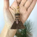 Close-up of decorative mini broom with pink gemstone pendant and natural brown fibers - Broom with Irregular Strawberry Quartz