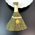 Macro detail of decorative straw broom featuring a golden sun pendant on dark background - Anthropomorphic Relief Sun Style (16)