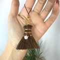 Detail of miniature handmade broom charm with fiber bristles and gold metal clasp - Broom with Rose Quartz