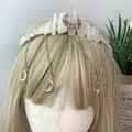 Detalle de corona de cristal natural con dijes de luna plateada y cadenas de borlas - Cuarzo rosa