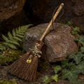 Detailansicht eines Hexenbesens mit Kristallanhänger auf Moos und Wald-Farnen - Bronze Hexe Gelber Kristall