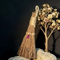 Dettaglio di un ciondolo a mini scopa di paglia con cristallo a goccia rosa su base in roccia - 17x8cm / Goccia d'acqua Rosa Rossa