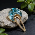 Macro detail of crescent moon hair clip with blue turquoise stones and gold metal finish - Apatite