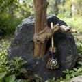 Close-up of handmade witch broom with silver sun pendant on rustic wood and moss - Broom With Small Sun