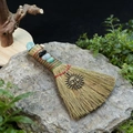 Detail of handmade witch broom with natural stones and golden sun charm on gray stone - Smiling Sun + Apatite