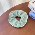 Chouchou en velours côtelé vert menthe avec bordure crème sur table en bois - Vert macaron