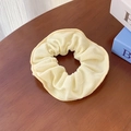 Chouchou élastique en maille gaufrée jaune pâle crème sur une table en bois - Beige