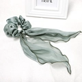 Detail view of large sage green satin bow scrunchie with long wavy ribbons and silky texture - Mint Green Streamer Scrunchie