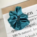 Donkergroene oversized satijnen scrunchie met zijdeachtige plooien op een papieren zak - Satijn Smaragdgroen