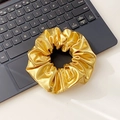 Elastico per capelli in pelle dorata metallizzata appoggiato su tastiera di laptop - Elastico per capelli / Oro