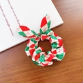Weihnachts-Haargummi mit Hasenohren und rot-grünem Karomuster auf einem Holztisch - Hasenohren Haargummi / Rot Grün Rautenmuster