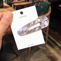 Handheld view of a grey marble pattern acetate hair clip on a white display card - Waterdrop Style / Gray