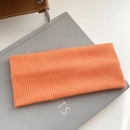 Elastic knitted wide headband in bright orange rib-knit texture on minimalist book - Orange