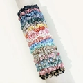 Close-up of assorted floral and solid color satin scrunchies displayed on a white stand - Floral and Solid Mix Style Eight