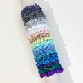 Detail view of colorful satin scrunchies set on a grey cylindrical display stand - Glossy Satin Style Seven