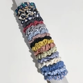 Set of 20 floral and solid color satin scrunchies displayed on a grey display pillar - Main Image Mixed Patterns