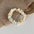 Detailed view of white mesh scrunchie with orange tulip prints on brown paper - Yellow