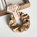 Chouchou élégant en satin doré avec texture soie sur un présentoir à bijoux - Chameau