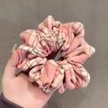 Pink and white plaid scrunchie with soft fabric pleats shown in hand - Pink