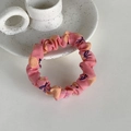 Detailed view of a pink floral fabric scrunchie with orange flower prints on a white tray - Apricot