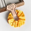 Chouchou élégant en satin jaune présenté sur une carte à bijoux en forme de losange - Orange