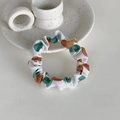 Detail of white scrunchie with green dots on a ceramic tray for hair styling - Orange