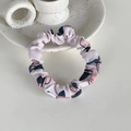Détail d'un chouchou en tissu rose avec motif fraise sur un support en céramique blanc - Mangue Rose