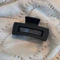 Matte black 8cm rectangular hollow hair claw clip shown on white knit sweater - Medium Rectangular Style (2# Matte)