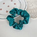 Elegant dark green satin scrunchie with silky finish on a decorative lace background - Teal