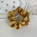 Elegant champagne gold satin scrunchie with a glossy finish for hair styling - Yellow