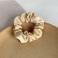 Elegant champagne gold satin scrunchie with pleated design on ceramic plate - Khaki