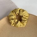 Elegant mustard yellow satin scrunchie with silky texture on a wooden tray - Yellow