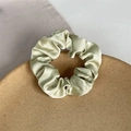 Elegant pale green satin scrunchie with silky pleated texture on a cork tray - Pale Green