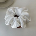 Vue détaillée de la texture satinée lisse et des plis élégants du chouchou en soie blanche - Blanc