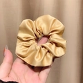 Champagne gold satin scrunchie with high elasticity and elegant silk texture shown in hand - Yellow
