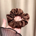 Minimalist brown satin scrunchie with high gloss silk texture held in hand - Coffee