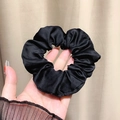 Classic black satin scrunchie with silk gloss finish held in hand for hair styling - Black