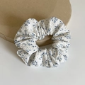 Elastico per capelli con fiori blu su tessuto bianco mostrato su supporto tondo - Medio / Floreale Blu