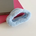 Chouchou en fausse fourrure bleu clair duveteux présenté sur des livres - Bleu